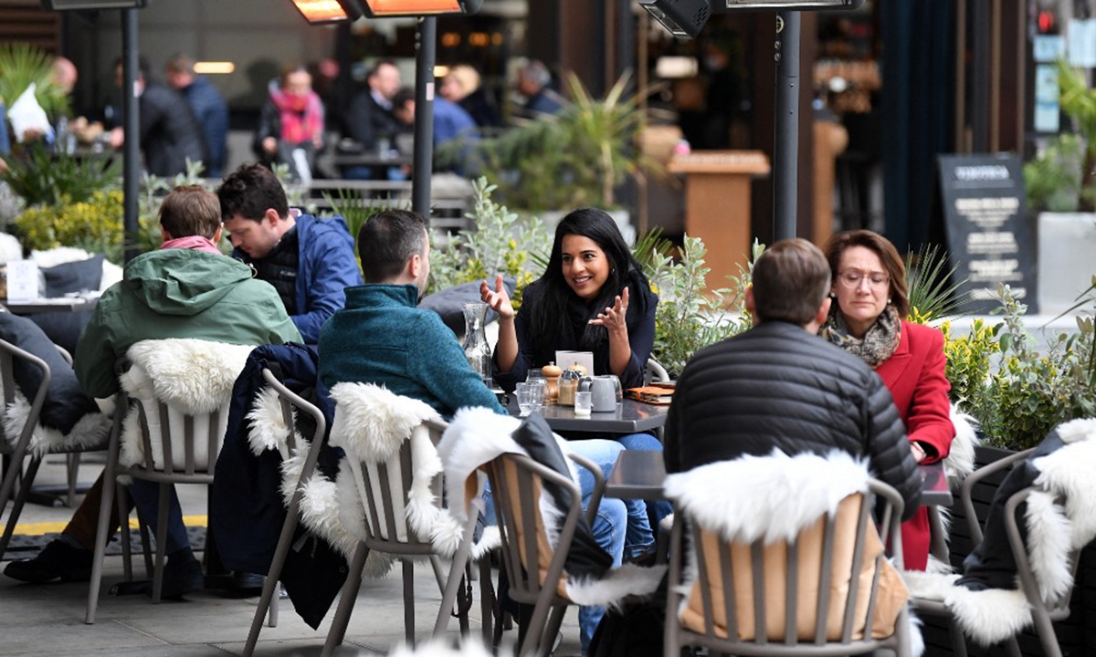 People eat and drink while sitting at tables outside a restaurant in London on April 29, 2021 Photo: AFP