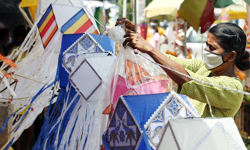 A vendor wearing a face mask prepares to sell lanterns ahead of the Vesak festival in Colombo, Sri Lanka, on May 19, 2021. The Vesak Festival is one of the holiest festivals celebrated in Sri Lanka as it marks the birth, enlightenment and demise of Lord Buddha.Photo:Xinhua