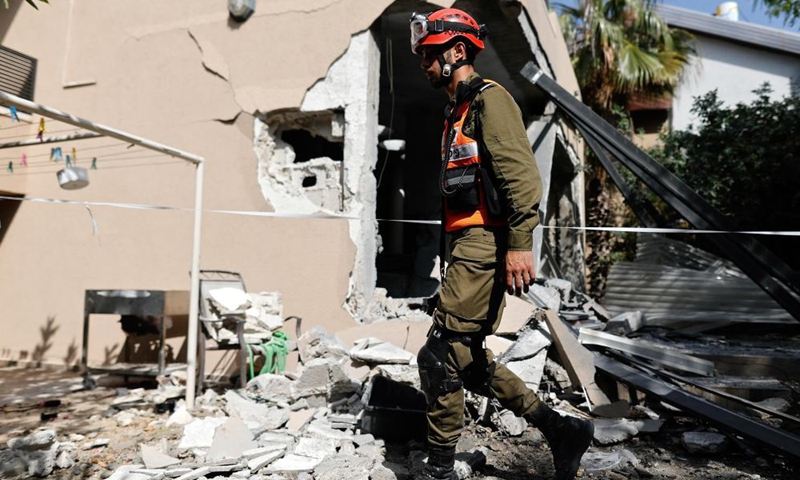 An Israeli rescue team member walks past a site hit by a rocket fired from the Gaza Strip, in Ashkelon, southern Israel, on May 20, 2021.Photo:Xinhua