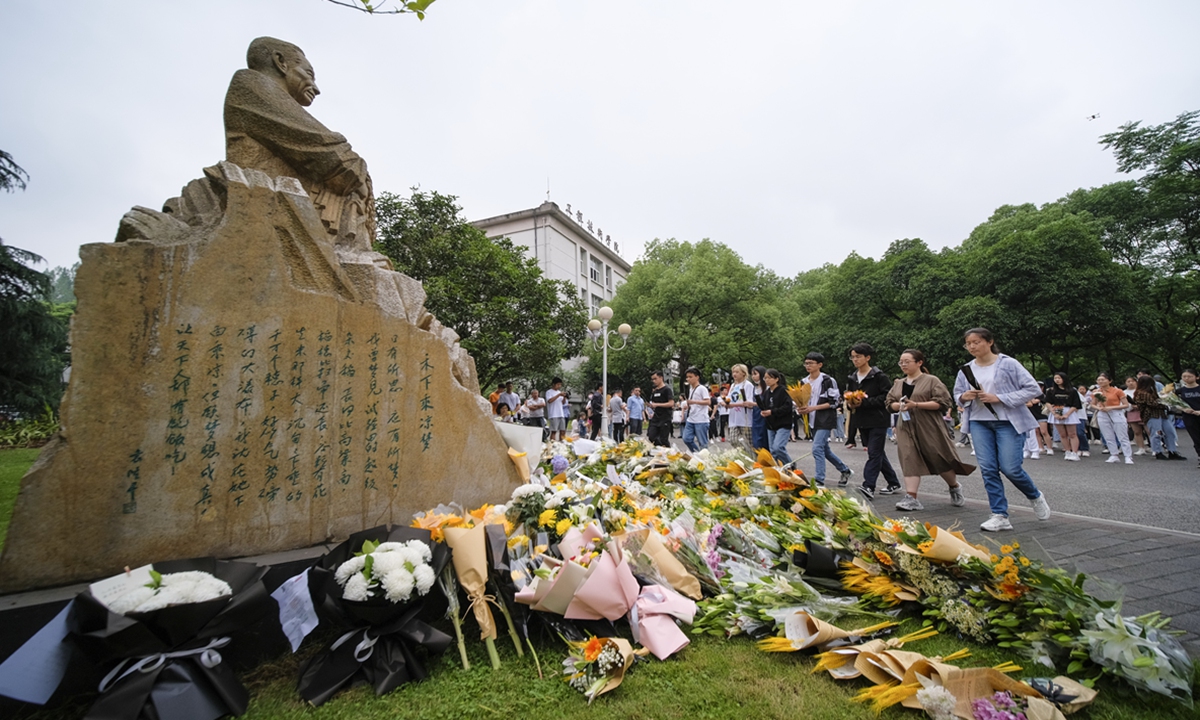 Students place flowers before of a statue of Yuan Longping in Southwest University in Chongqing on Sunday. Photo: IC