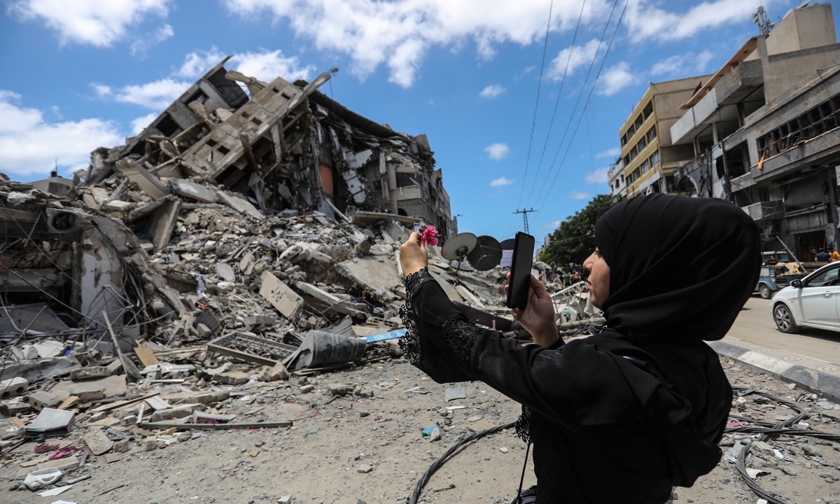 Palestinian woman takes a selfie near the rubble in Gaza city on Saturday, Gazans tried to piece back their lives after a devastating 11-day conflict with Israel that killed more than 200 people and made thousands homeless in the impoverished Palestinian enclave. Photo: VCG