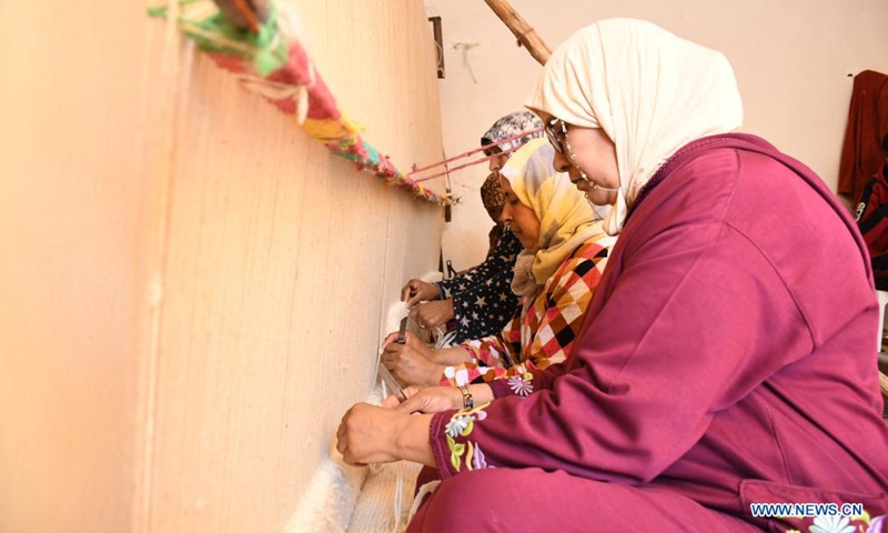 Women weave a traditional carpet in Tiflet, Morocco, on May 23, 2021. The Tiflet region is famous for berber-style handwoven carpets. (Photo by Chadi/Xinhua)
