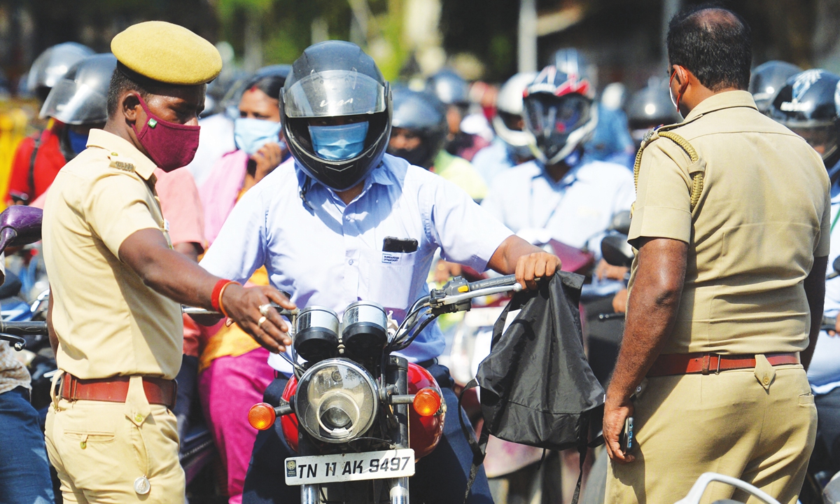 Police personnel inquire about the traveling details of commuters after a complete lockdown was imposed by the state government as a preventive measure against the spread of the COVID-19 in Chennai, India, on Monday, as India passed more than 300,000 deaths from the coronavirus pandemic. Photo: AFP