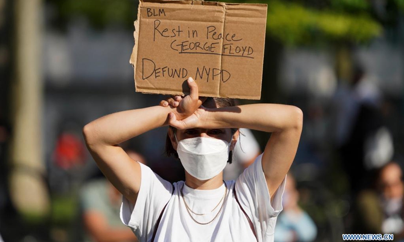 A woman holding a sign attends a rally to mark the one-year anniversary of George Floyd's death in Cadman Plaza Park in New York, the United States, May 25, 2021.(Photo: Xinhua)