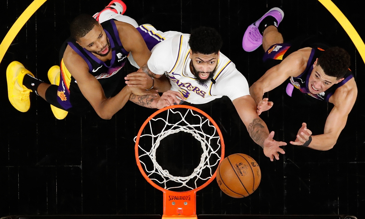 Anthony Davis (center) of the Los Angeles Lakers reaches for a rebound over Mikal Bridges (left) and Devin Booker of the Phoenix Suns on Sunday in Phoenix, Arizona. Photo: VCG