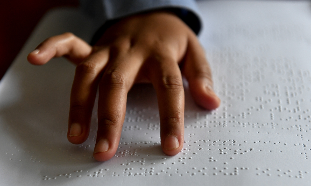 A visually impaired student reads Braille during an online class on World Braille Day on January 04, 2021 in Surabaya, Indonesia. Photo: VCG