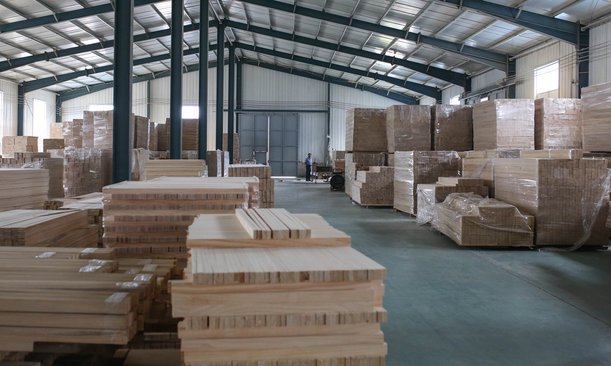 Two workers lift up a coffin in a factory in Caoxian county, East China's Shandong Province in July 2019. Photo: IC