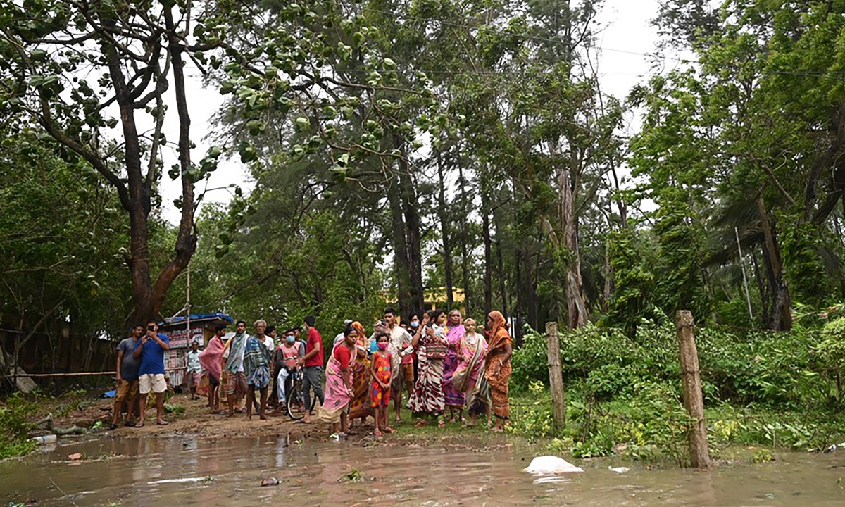 Residents stand near a shelter while sea water floods a road as Cyclone Yaas barrels toward India's eastern coast in the Bay of Bengal on Wednesday. Photo: AFP