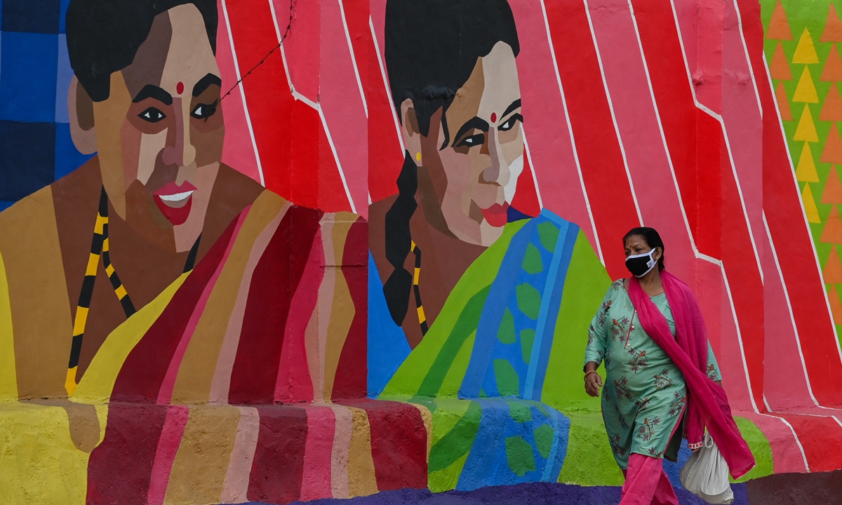 A woman walks along a street past a mural depicting transgender women to raise awareness about the transgender community in Mumbai, India on Wednesday. With several restrictions in place across the state, members of the community say that their livelihoods have been affected. Photo: AFP