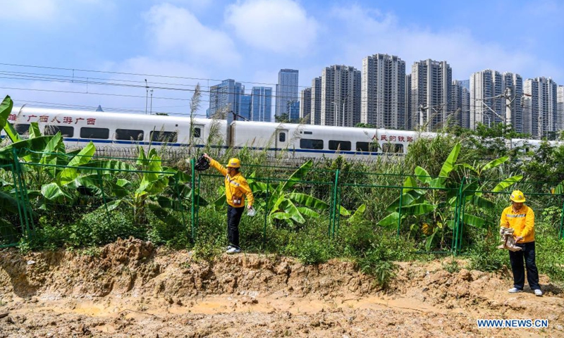 Railway staff members pick up light objects near a railroad section in Nanning, south China's Guangxi Zhuang Autonomous Region, May 26, 2021. (Photo by Duan Yanan/Xinhua)