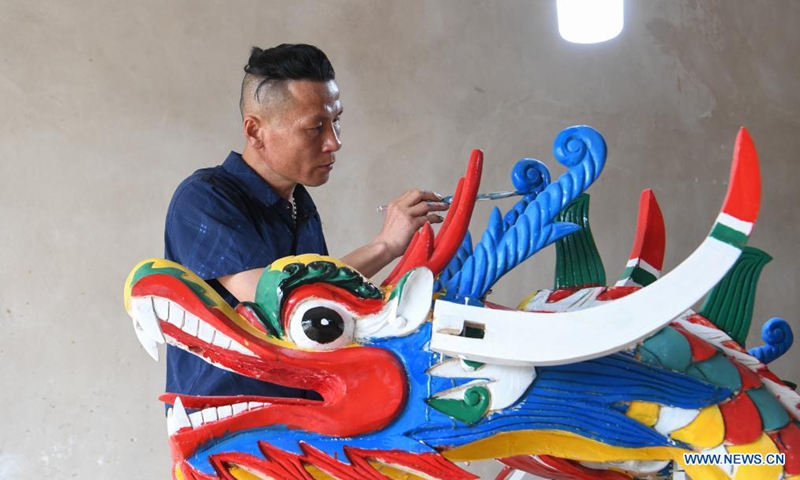 A handicraftsman paints a dragon head for dragon boat in Chengguan Township, Shibing County of Qiandongnan Miao and Dong Autonomous Prefecture, southwest China's Guizhou Province, May 30, 2021. Handicraftsmen here are busy making dragon heads, a part of dragon boats for the contests during the upcoming Dragon Boat Festival. (Photo by Liang Wen/Xinhua)