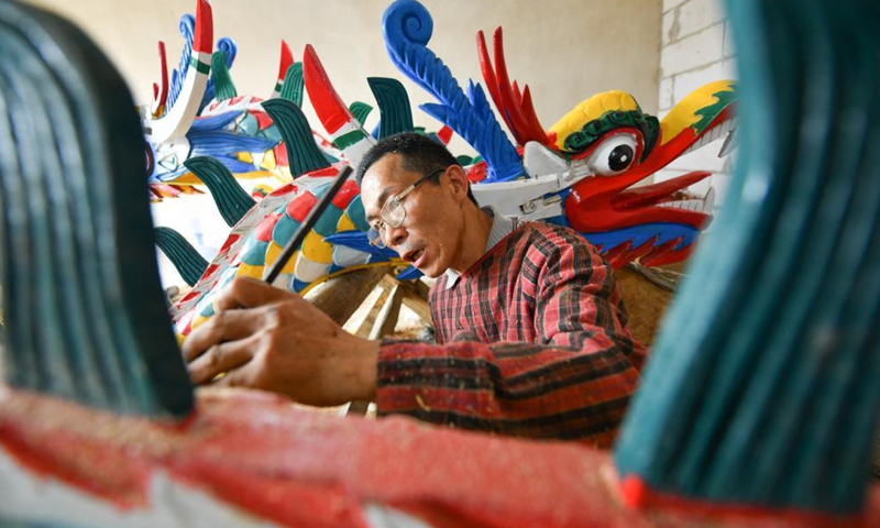 A handicraftsman makes a dragon head for dragon boat in Chengguan Township, Shibing County of Qiandongnan Miao and Dong Autonomous Prefecture, southwest China's Guizhou Province, May 30, 2021. Handicraftsmen here are busy making dragon heads, a part of dragon boats for the contests during the upcoming Dragon Boat Festival. (Photo by Liang Wen/Xinhua)