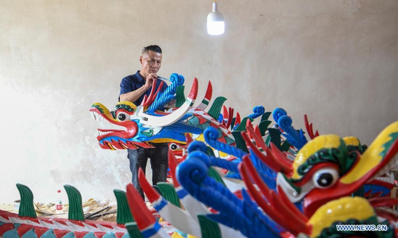 A handicraftsman paints a dragon head for dragon boat in Chengguan Township, Shibing County of Qiandongnan Miao and Dong Autonomous Prefecture, southwest China's Guizhou Province, May 30, 2021. Handicraftsmen here are busy making dragon heads, a part of dragon boats for the contests during the upcoming Dragon Boat Festival. (Photo by Liang Wen/Xinhua)