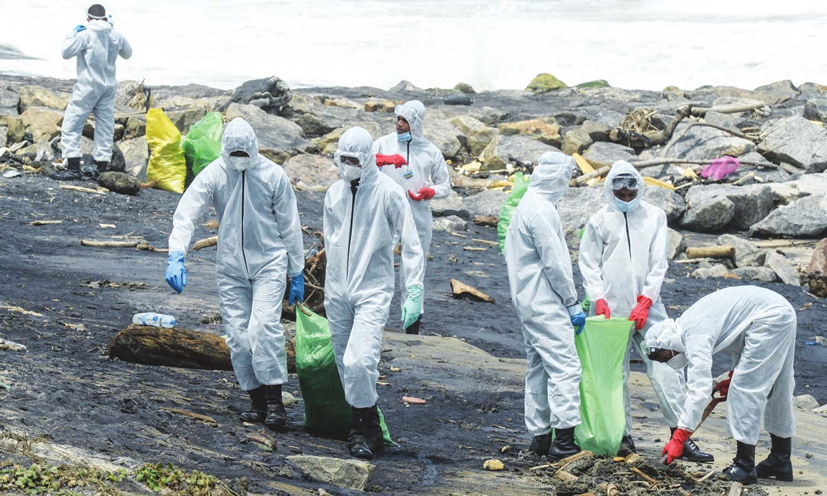 On Sunday, Sri Lanka's Air force personnel remove debris washed ashore from the Singapore- registered container ship MV X-Press Pearl, which has been burning for the eleventh consecutive day in the sea off Colombo Harbour. Photo: AFP
