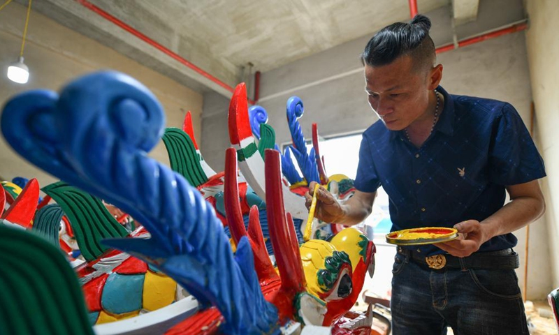 A handicraftsman paints a dragon head for dragon boat in Chengguan Township, Shibing County of Qiandongnan Miao and Dong Autonomous Prefecture, southwest China's Guizhou Province, May 30, 2021. Handicraftsmen here are busy making dragon heads, a part of dragon boats for the contests during the upcoming Dragon Boat Festival. (Photo by Liang Wen/Xinhua)
