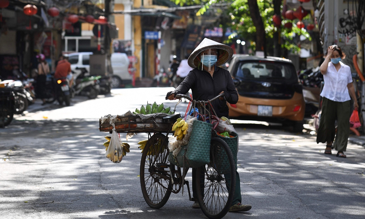 A fruit vendor walks her bike along a street in Hanoi on May 28, 2021. Photo: VCG