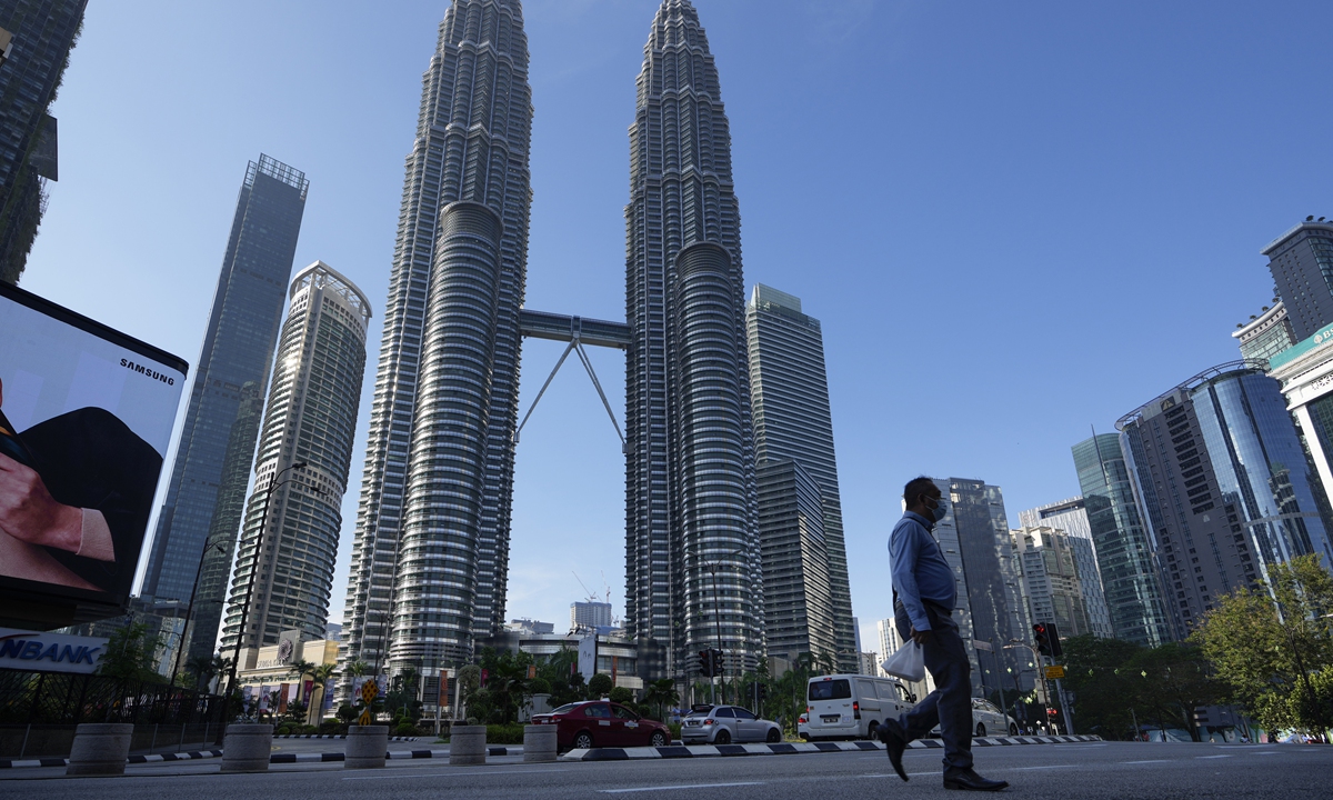 A man wearing a face mask walks along an empty road in front of the Twin Towers during the first day of Full Movement Control Order (MCO) in Kuala Lumpur, Malaysia, on Tuesday, when the country reported 7,105 cases. Malls and most businesses closed as the country began its second near total lockdown to tackle a worsening epidemic. 
Photo: VCG
