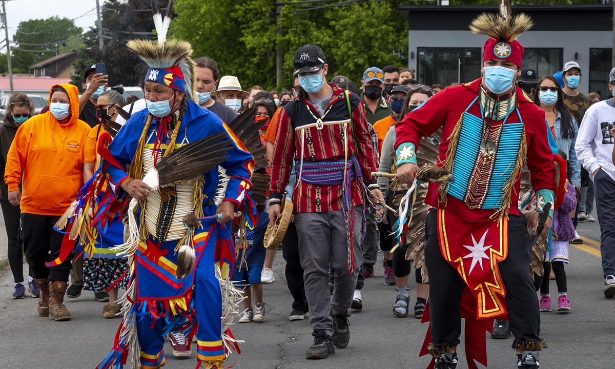 Members of the community of the Kahnawake Mohawk Territory, Quebec march through the town on May 30, 2021, to commemorate the news that a mass grave of 215 Indigenous children were found at the Kamloops Residential School in British Columbia, Canada. Photo: AFP