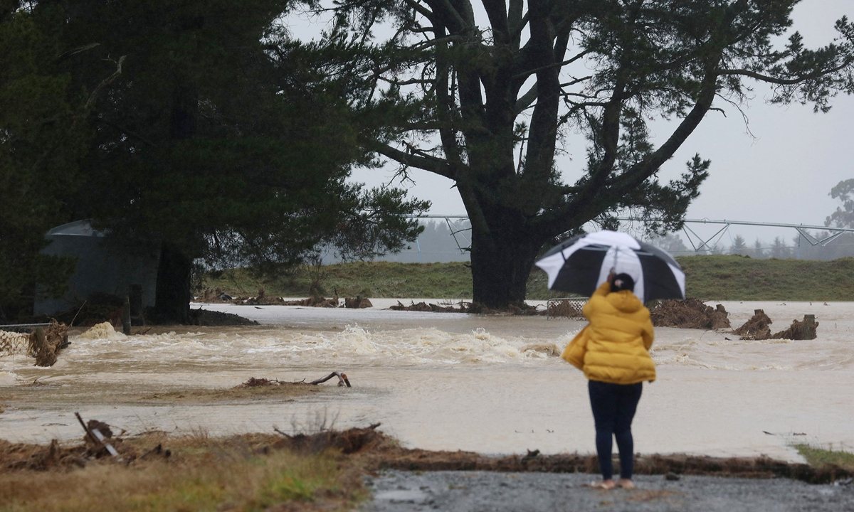 A woman looks at farmland flooded by the swollen Hawkins River in the Greendale area of Canterbury Province, New Zealand on Monday, after the area was pounded by heavy rains that forced authorities to declare a state of emergency in the province. Photo: AFP