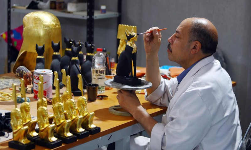 A painter colors a replica of a golden-blue scarab at Konouz Egypt Replica Treasures in Qalyubia, Egypt, on May 25, 2021. Dozens of designers, sculptors, painters and workers, were busy producing replicas of ancient Egyptian artifacts at Konouz Egypt Replica Treasures, the first factory in Egypt and the Middle East for producing replicas of historical Egyptian antiquities.Photo:Xinhua 