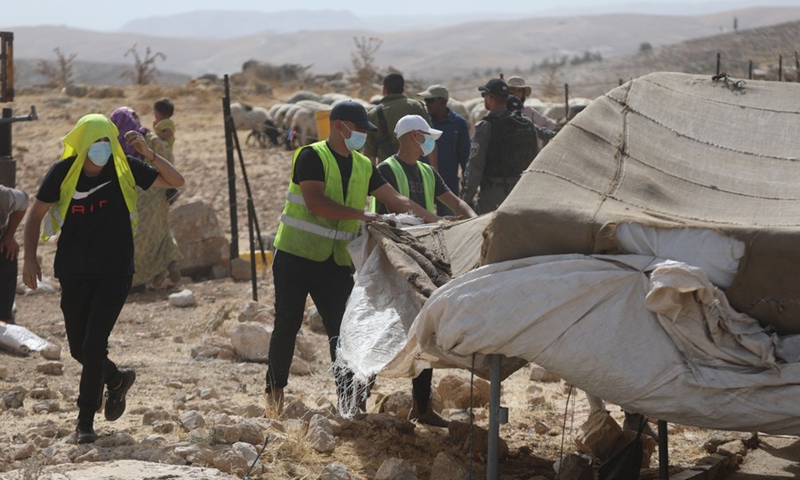 laborers work on confiscation of a tent as israeli soldiers and