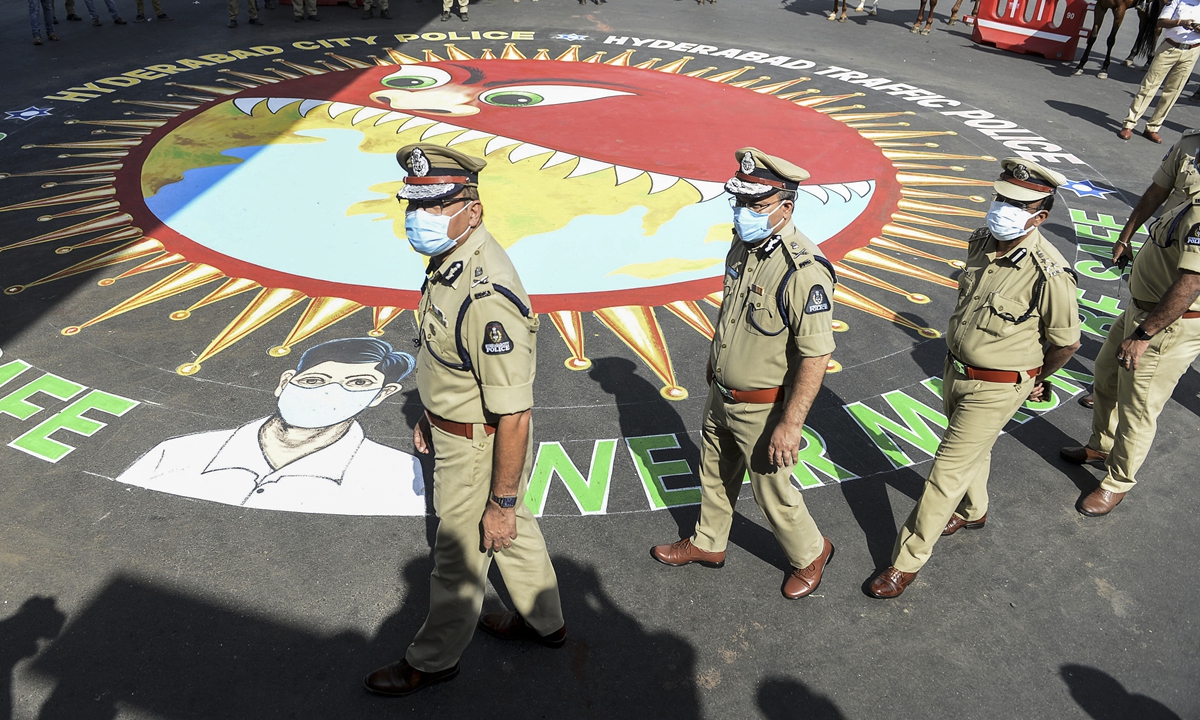 Police officers walk around graffiti depicting COVID-19 coronavirus safety protocols during an awareness campaign in Hyderabad, India, on Tuesday. India reported more than 28 million cases as of Tuesday, the second most in the world following the US. Photo: AFP