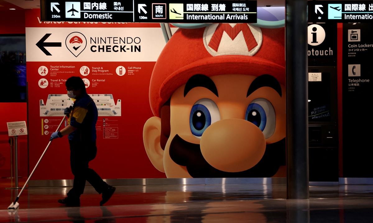 A janitor mops the floor in front of a sign featuring Nintendo game character Mario at Narita Airport in Chiba Prefecture, Japan on Tuesday. Japan reported more than 747,000 coronavirus infections and 13, 006 fatalities as of Tuesday. Photo: AFP