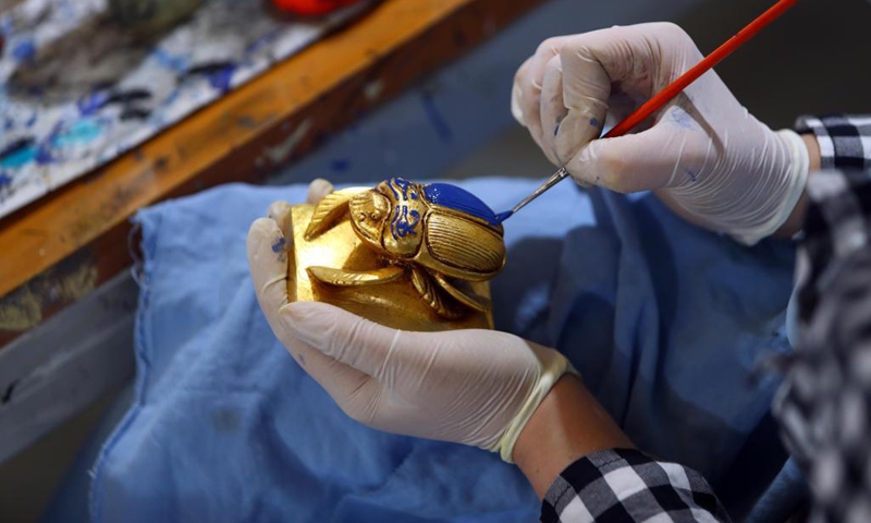 A painter colors a replica of a golden-blue scarab at Konouz Egypt Replica Treasures in Qalyubia, Egypt, on May 25, 2021. Dozens of designers, sculptors, painters and workers, were busy producing replicas of ancient Egyptian artifacts at Konouz Egypt Replica Treasures, the first factory in Egypt and the Middle East for producing replicas of historical Egyptian antiquities.Photo:Xinhua 
