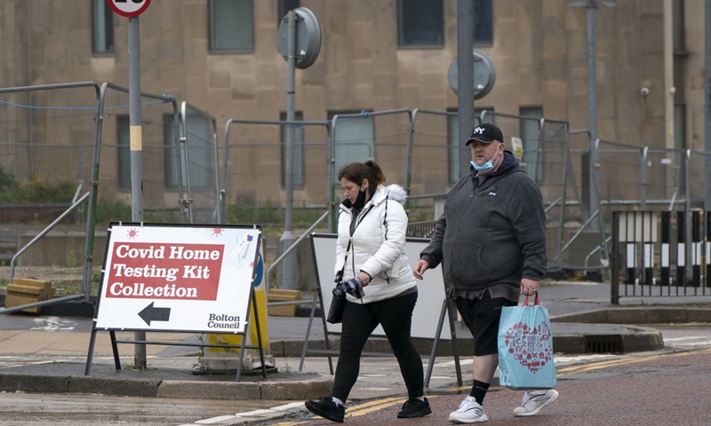 People walk past a COVID-19 home testing kit collection center in Bolton, Britain, on May 21, 2021.(Photo: Xinhua)