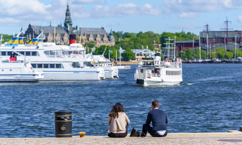 People enjoy the sunshine by the sea in Stockholm, Sweden on June 1, 2021. From June 1, Sweden has started the first steps to ease the country's COVID-19 restrictions, meaning that restaurants can open longer, and public events can accommodate more people. (Photo by Wei Xuechao/Xinhua)