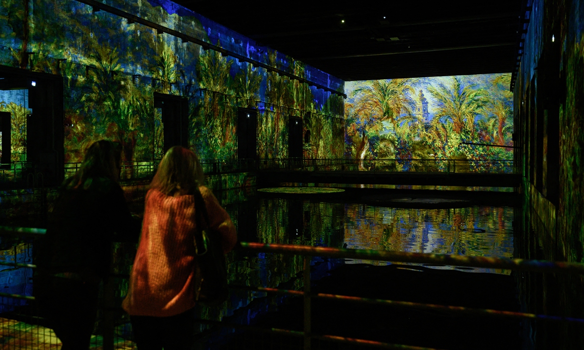 Two women look at projections of paintings by Danish-French Impressionist Camille Pissarro during a press visit of the digital exhibition in Bordeaux, France on May 11. Photo: AFP