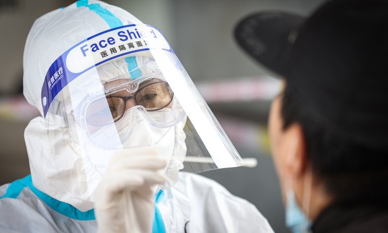 A medical worker collects a swab sample for nucleic acid testing of possible COVID-19 infection from a resident at a testing site in the Xin'gang residential compound in Bayuquan District, Yingkou City, northeast China's Liaoning Province, on May 21, 2021.Photo: Xinhua
