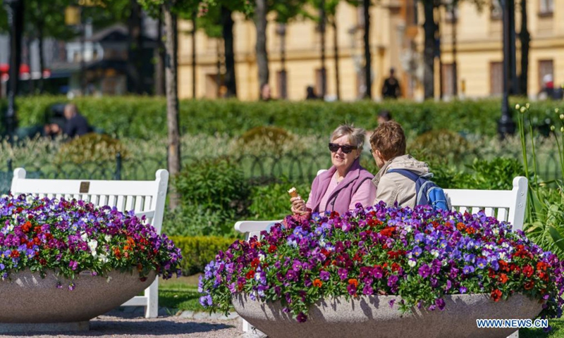 People enjoy the sunshine in a park in Stockholm, Sweden on June 1, 2021. From June 1, Sweden has started the first steps to ease the country's COVID-19 restrictions, meaning that restaurants can open longer, and public events can accommodate more people. (Photo by Wei Xuechao/Xinhua)
