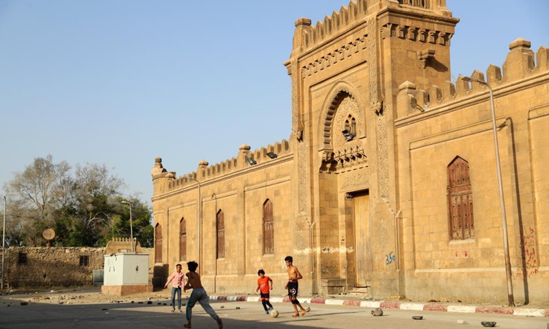 A child plays football on an open space at a slum area with cemeteries, in Cairo, Egypt, June 1, 2021. Children living in the slum enjoy themselves by playing football on a simply-equipped football field on Tuesday that marks the International Children's Day.(Photo: Xinhua)