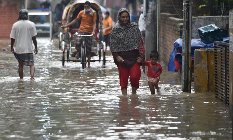 People wade through a waterlogged street at a low lying area in Bangladeshi capital Dhaka, June 1, 2021. Heavy rain lashed Dhaka on Tuesday morning, inundating low-lying areas and disrupting road traffic.(Photo: Xinhua)