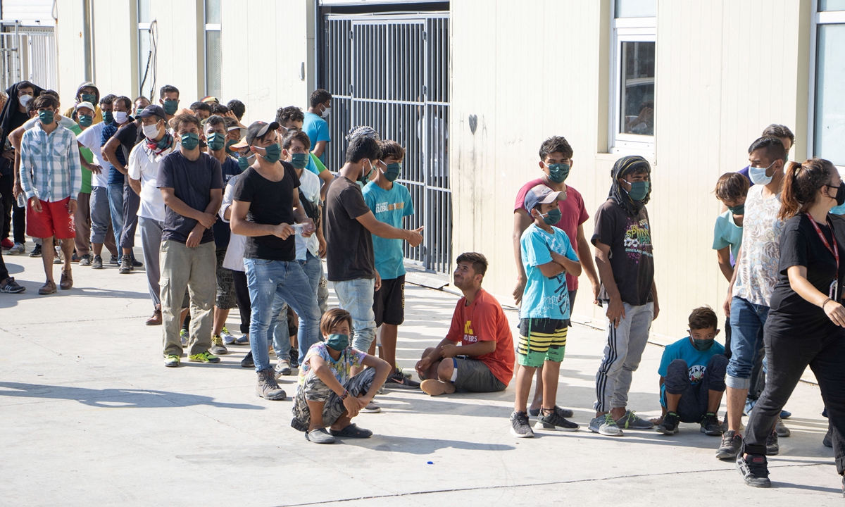 Asylum seekers wait in line to have their body temperature tested from Team Humanity Denmark NGO on Lesbos Island, Greece on September 20, 2020. Photo: AFP