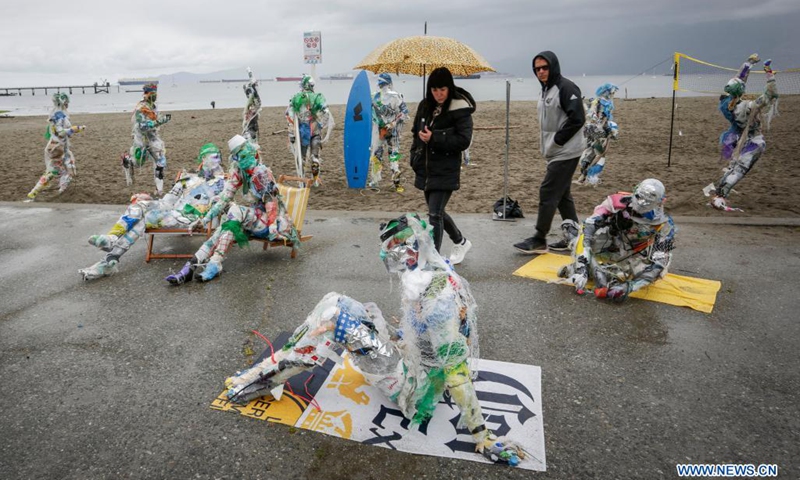 People look at figures made with plastics removed from shorelines at Kitsilano Beach in Vancouver, British Columbia, Canada, on June 6, 2021. Created by multidisciplinary artist Caitlin Doherty and made with plastics removed from Canadian shorelines, a set of figures named plastic beachgoers embody people's collective contribution to plastic pollution, bring the topic of shoreline pollution to the forefront.(Photo: Xinhua)