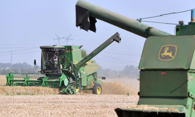 Farmers operate harvesters in a wheat field in Zhoukou, central China's Henan Province, June 6, 2021. Farmers have been busy with summer harvesting activities in Henan Province, a major wheat producing area. (Xinhua/Li Jianan)