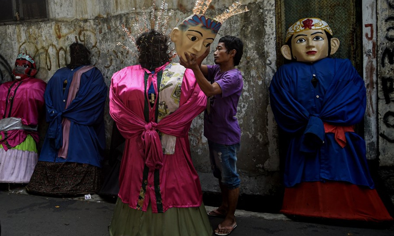 A man takes off the mask of a Ondel-Ondel in Jakarta, Indonesia, June 7, 2021.(Photo: Xinhua)