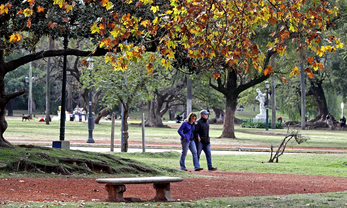 A couple wearing protective face masks walk at a park in Palermo neighborhood in Buenos Aires, Argentina on Saturday. People have been mobilizing in various cities around the country to protest against the isolation policies that the government has adopted to combat the ongoing coronavirus pandemic. Photo: AFP