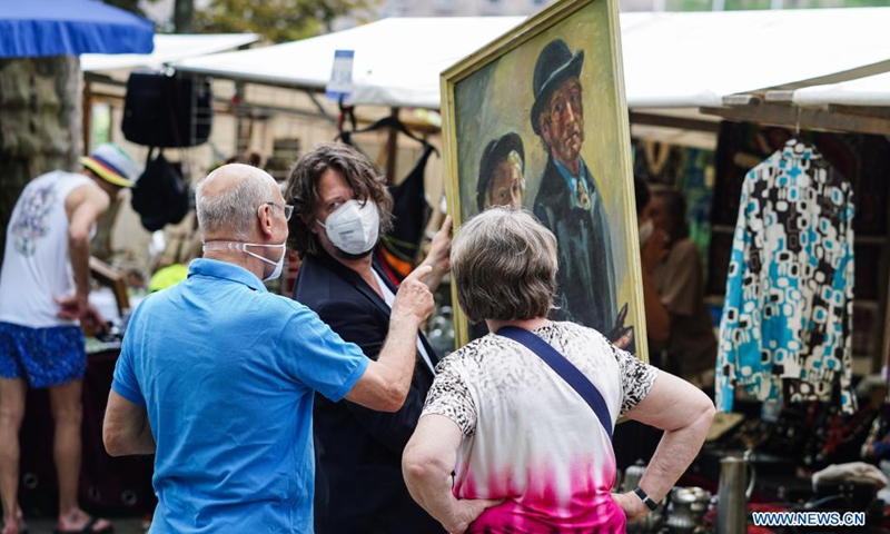 People select a painting at a flea market in Berlin, Germany, June 6, 2021. Flea markets are allowed to reopen from June 4 after longtime closure due to COVID-19 pandemic, attracting many visitors at the weekend.(Photo: Xinhua)