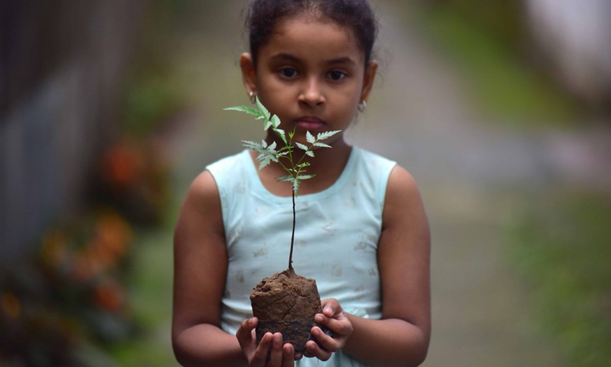 A girl holds a tree sapling on the occasion of World Environment Day in Nagaon of Assam, India, June 5, 2021. (Str/Xinhua)