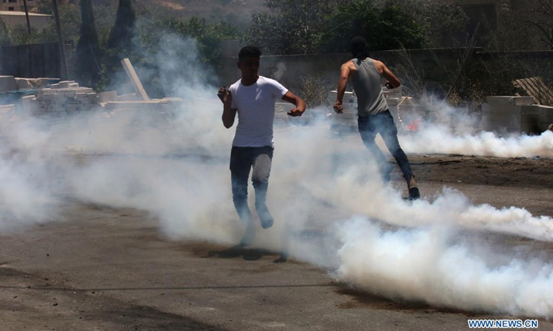 Palestinian protesters run to take cover from tear gas canisters fired by Israeli security forces during a protest against the expanding of Jewish settlements and the Israeli annexation plan in the village of Beita, south of the West Bank city of Nablus, on June 8, 2021.(Photo: Xinhua)