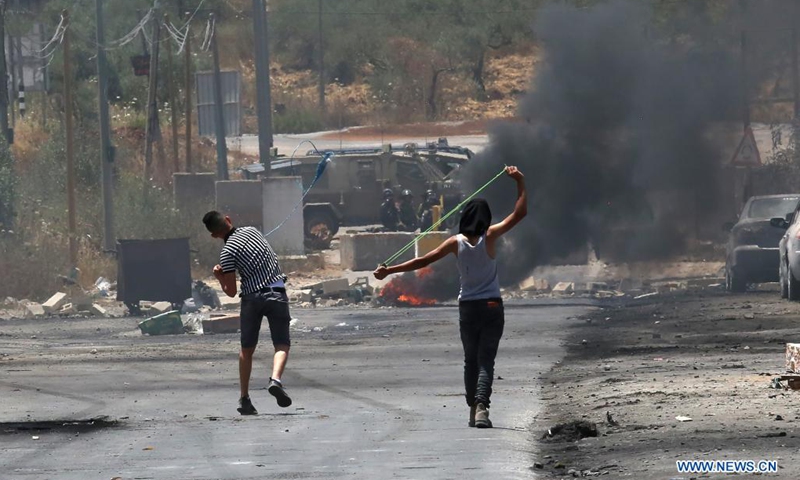 Palestinian protesters use slingshots to hurl stones at Israeli security forces during a protest against the expanding of Jewish settlements and the Israeli annexation plan in the village of Beita, south of the West Bank city of Nablus, on June 8, 2021. (Photo: Xinhua)