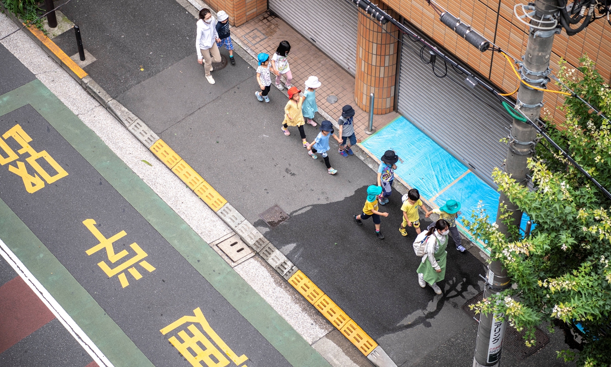 Children accompanied by guardians walk to a kindergarten in Tokyo on Monday. Photo: AFP