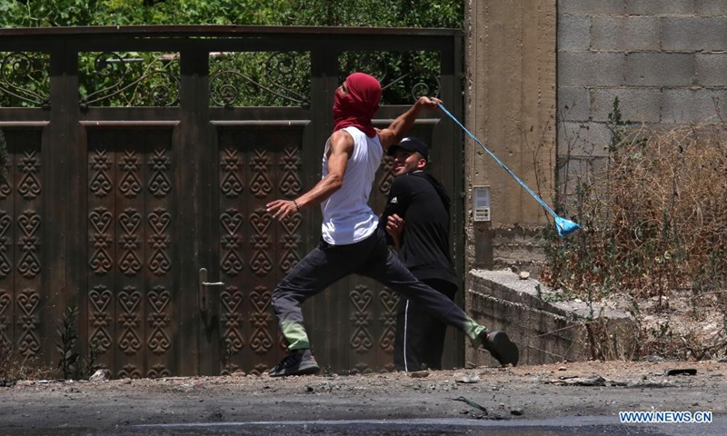 A Palestinian protester uses a slingshot to hurl a stone at Israeli security forces during a protest against the expanding of Jewish settlements and the Israeli annexation plan in the village of Beita, south of the West Bank city of Nablus, on June 8, 2021.(Photo: Xinhua)