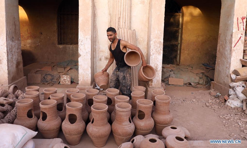 A worker carries dried potteries at a workshop in Fustat Pottery City in Cairo, Egypt, June 8, 2021. Fustat Pottery City is a pottery making and selling place where you can find a broad range of unique pottery items. Pottery workshop owners here now suffer from stagnation in business due to the COVID-19 pandemic.Photo: Xinhua