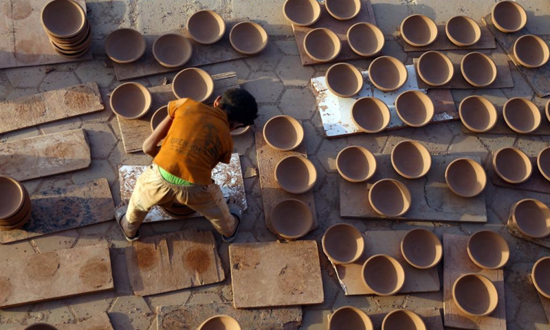 A worker arranges dried potteries at a workshop in Fustat Pottery City in Cairo, Egypt, June 8, 2021. Fustat Pottery City is a pottery making and selling place where you can find a broad range of unique pottery items. Pottery workshop owners here now suffer from stagnation in business due to the COVID-19 pandemic.Photo: Xinhua