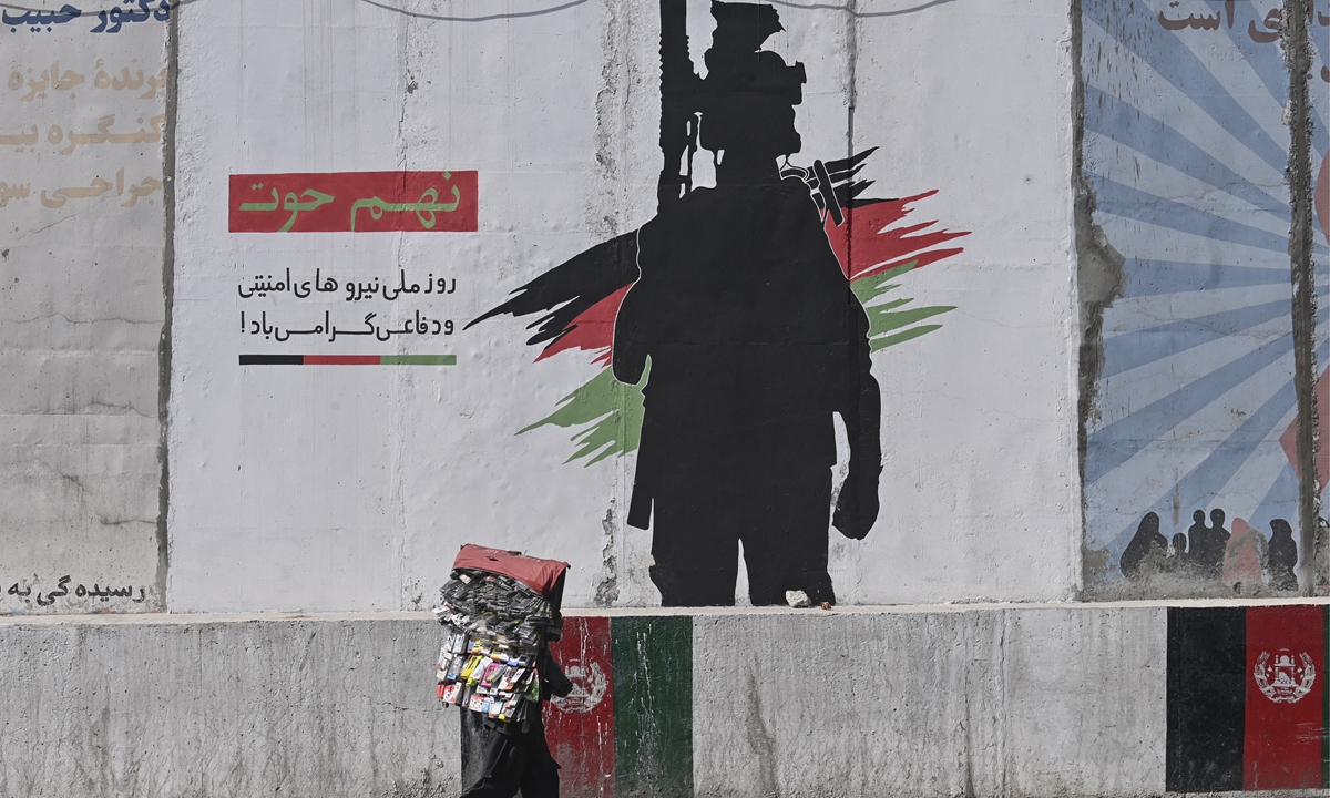 A street vendor carrying his merchandise walks past a mural depicting an Afghan National Army soldier in Kabul, Afghanistan on Thursday. The Afghan National Army is the land warfare branch of the Afghan Armed Forces. It is under the Ministry of Defense in Kabul and is largely trained by US-led NATO forces. Photo: AFP