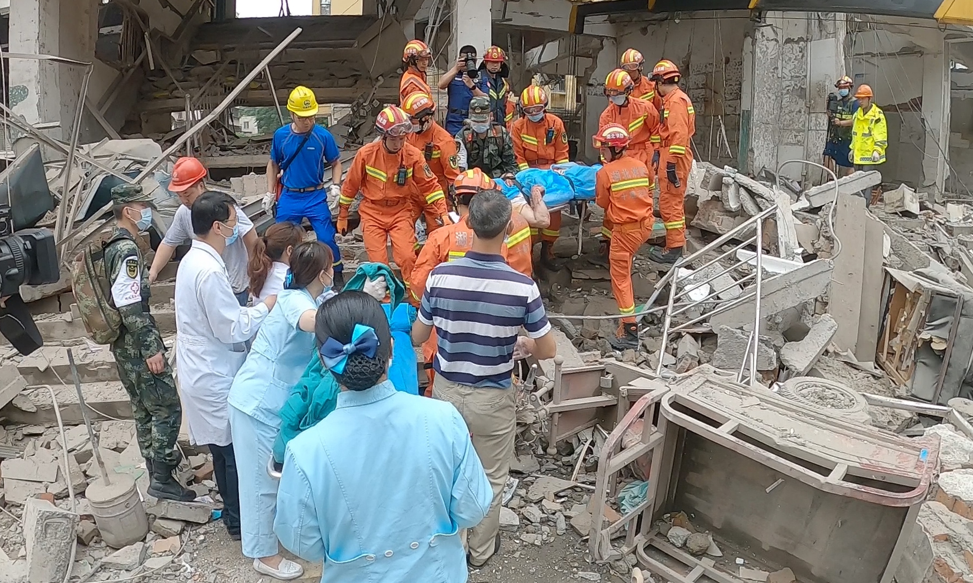 Firefighters carry a person injured in a gas explosion in a residential community in Shiyan, Central China's Hubei Province. The accident killed 25 and injured 138, according to information available as of Monday afternoon.  Rescue work and investigation of the cause are still in progress. Photo: VCG